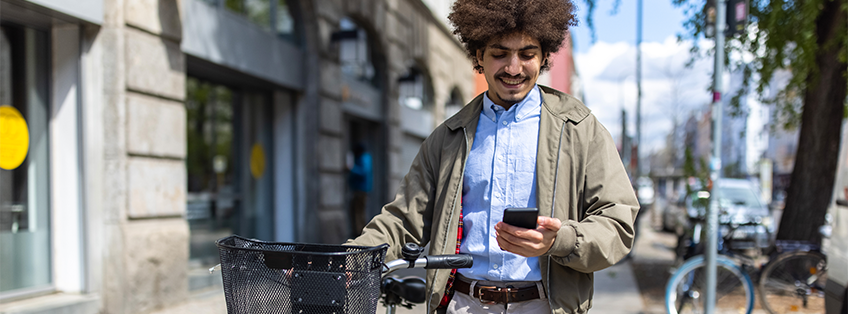 Mann mit Fahrrad kauft etwas auf seinem Smartphone